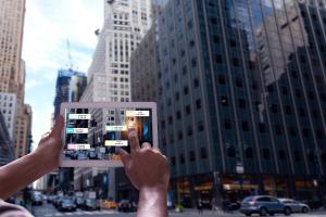 person holding tablet in front of skyscraper