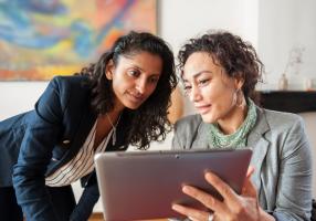 Two women comparing options on a tablet computer.