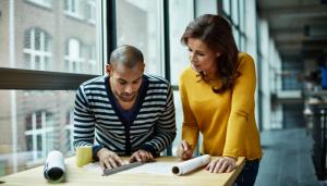 Color photo of man and woman at a drafting table in an office