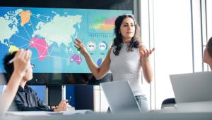 Woman gesticulating at world map chart in conference room