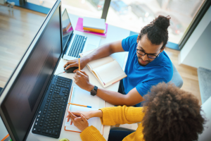 Overhead color shot of two coworkers in discussion in front of a computer monitor