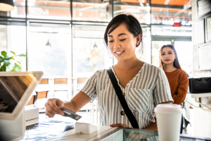 Color photo of young woman paying at a cafe with a credit card