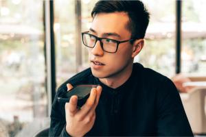 Color photo of bespectacled Asian man talking into a mobile phone
