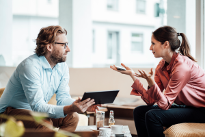 A man and woman conversing across a table 