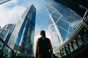 Color photo of the back of a woman looking up at skyscrapers