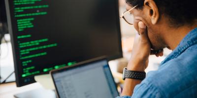 IT professional with desktop and laptop screen in front