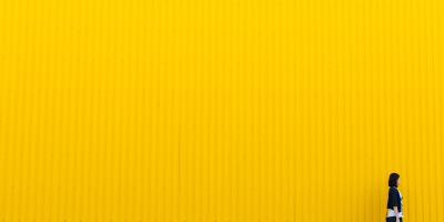 person walking in front of yellow wall