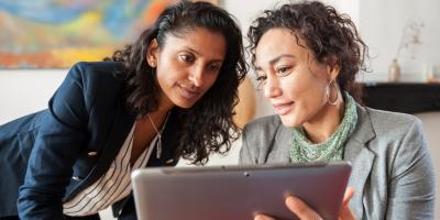 Two women comparing options on a tablet computer.