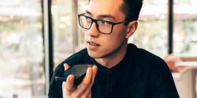 Color photo of bespectacled Asian man talking into a mobile phone