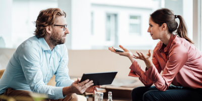 A man and woman conversing across a table 