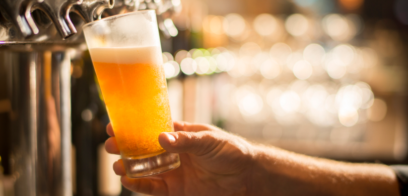 Filling beer glass at bar tap