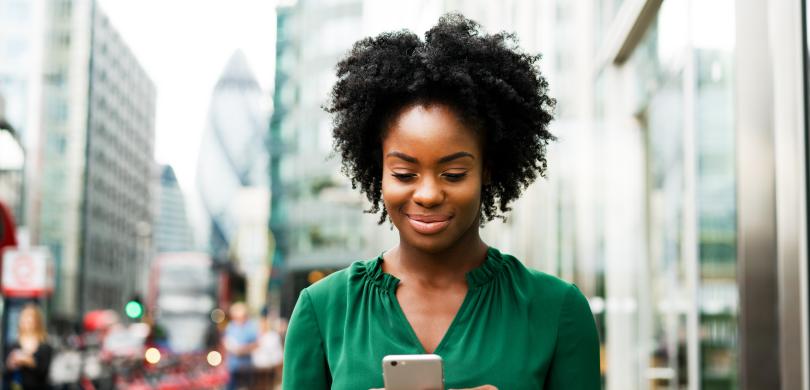 Woman on city street holding smartphone in two hands