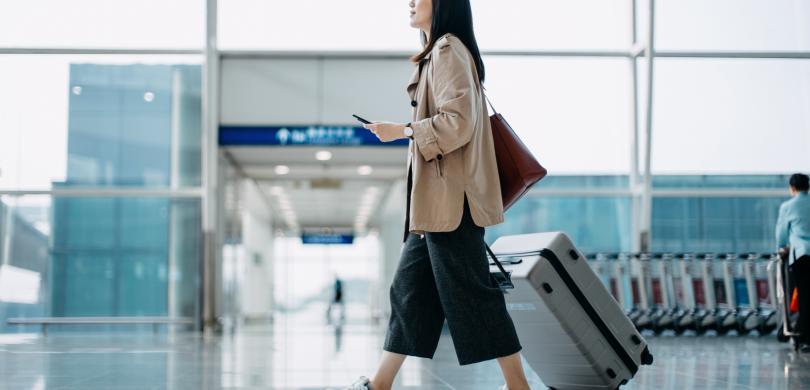 Woman walking through airport terminal with suitcase