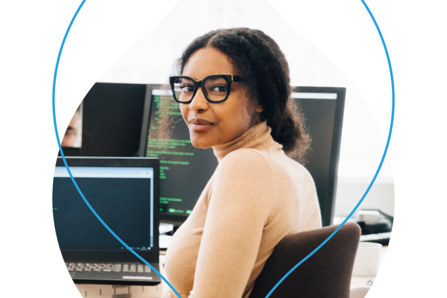 image of a person sitting at a desk with a laptop screen that has code on it masked in an acquia droplet