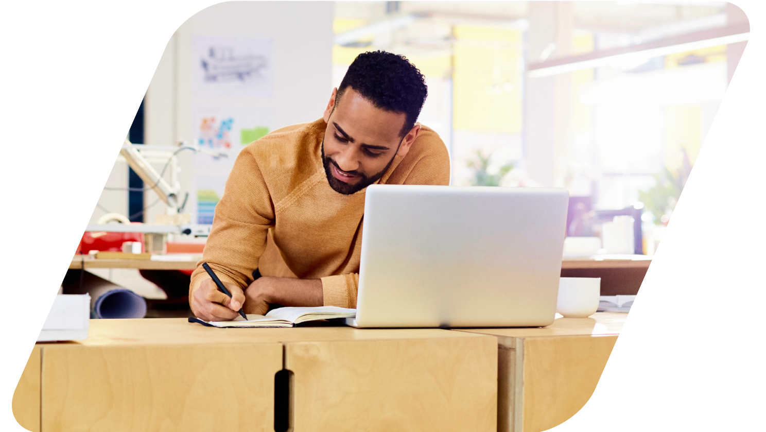 image of a person taking notes looking at laptop masked by a parallelogram