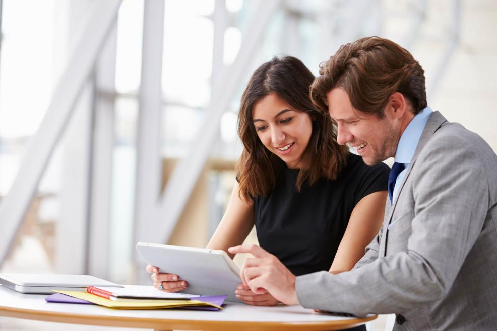 Two coworkers looking at a tablet together