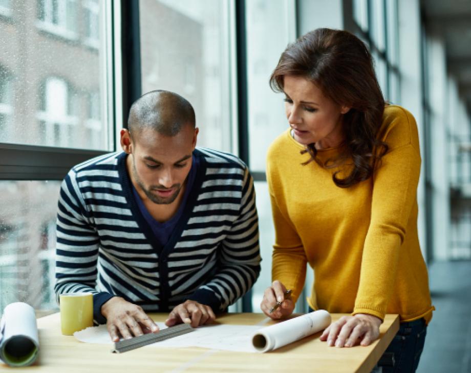 Color photo of man and woman at a drafting table in an office