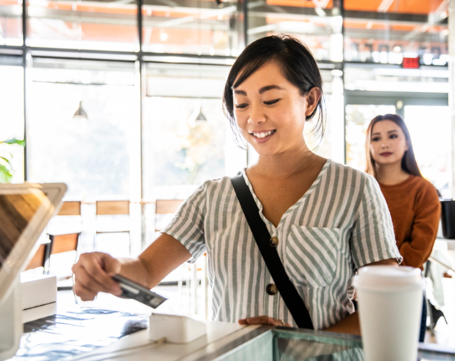 Color photo of young woman paying at a cafe with a credit card