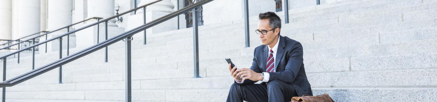 Man sitting on steps of courthouse using phone