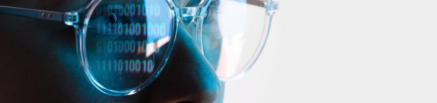 Upclose of face wearing glasses with code reflected in lenses