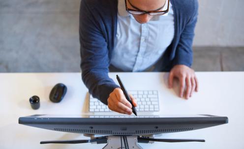 Aerial view of person holding stylus to computer monitor